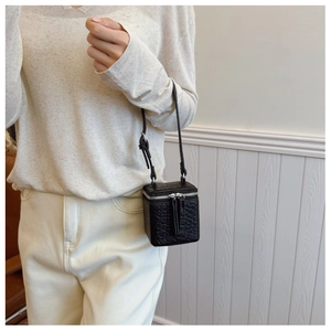 Detail view of the black crossbody box bag featuring textured faux animal leather and zippers