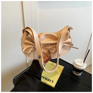 Dettaglio macro della borsa in raso champagne a pieghe con elegante fiocco decorativo