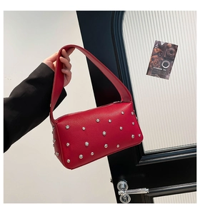 Dettaglio di una borsa in pelle litchi rossa con borchie argentate in stile punk rock