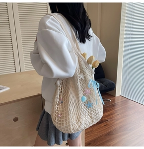 Detail of beige woven mesh tote bag with starfish charms and blue ribbon bow