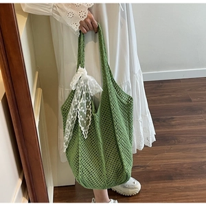 Détail du sac cabas au crochet vert avec nœud en dentelle blanche et texture