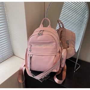 Detailed view of pink pebble grain leather backpack with matching mini pouch on wide strap