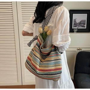 Detail of colorful striped straw tote bag with bow strap and floral accent