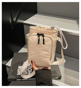 Detailed shot of cream mini crossbody bag with drawstring closure and front zip pocket