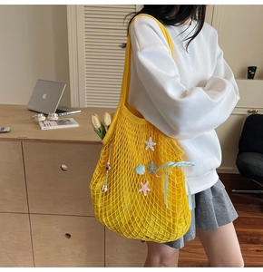 Detail of yellow woven tote bag with starfish charms and light blue ribbon bow