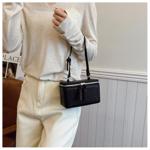 Detail view of black textured leather mini box bag with silver zippers and single strap