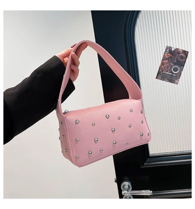 Dettaglio della borsa a mano in pelle rosa con borchie metalliche e ampio manico