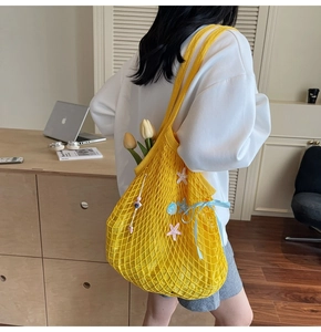 Detail of yellow woven tote bag with starfish, shells, and a blue ribbon bow detail