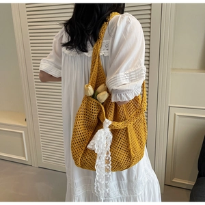 Détail d'un sac cabas en tricot jaune avec ruban de dentelle blanche et tulipes