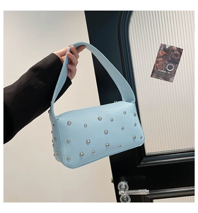 Dettaglio della borsa in pelle azzurra con borchie argento e texture martellata
