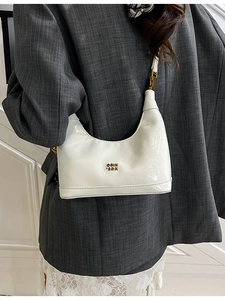 Borsa a mezzaluna in pelle cerata bianca con logo dorato indossata da una modella
