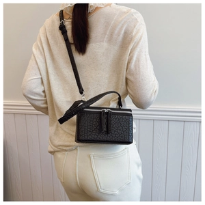 Detailed back view of a black textured leather box bag with silver hardware on a model