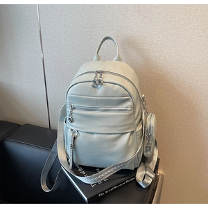 Detail of light green pebbled leather backpack with patterned woven straps on a black chair