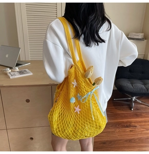 Detailed weave of bright yellow crochet tote with starfish and blue ribbon decor