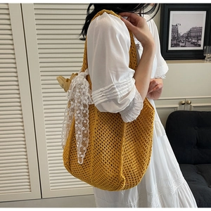 Détail d'un sac cabas en tricot jaune avec nœud en dentelle blanche et motif ajouré
