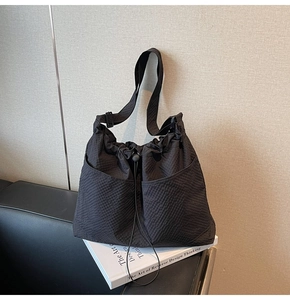Detailed view of the black tote bag showing its waffle texture fabric and adjustable strap