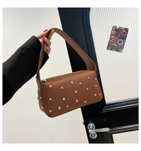 Dettaglio ravvicinato della borsa in pelle marrone con borchie argentate e stile retrò