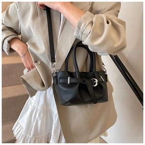 Détail du petit sac seau en cuir noir porté en bandoulière avec une sangle ajustable