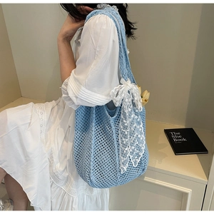 Détail du sac tricoté bleu clair avec nœud en dentelle et accent floral de tulipe