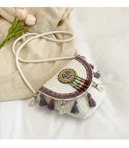Detail of woven white shoulder bag with colorful tassels and intricate beaded ornament