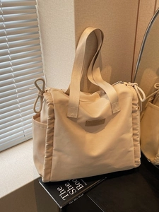 Grande borsa tote beige minimalista con pieghe laterali e spallacci in luce soffusa