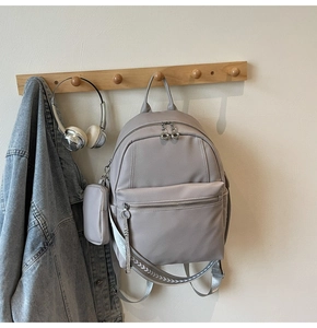 Detail of grey leather backpack with woven strap and coin pouch on a wooden hanger