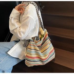 Dettaglio della grande borsa tote in paglia a righe colorate con spalline in bianco e nero