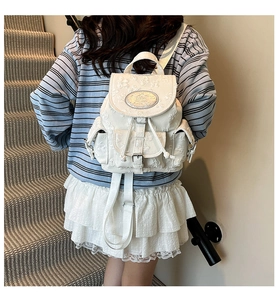Détail de la texture florale blanche et du logo de marque sur ce mini sac à dos en tissu