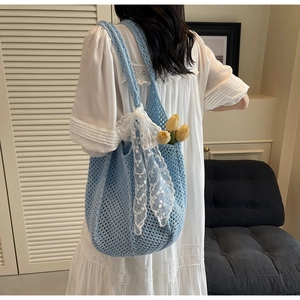 Détail du sac en tricot bleu clair avec un nœud en dentelle blanche et des fleurs