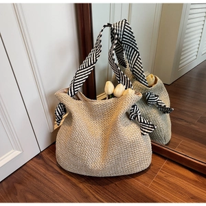 Dettaglio borsa tote in paglia beige con tracolla a righe bianche e nere e nodo