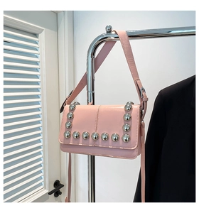 Detail of pink moto-style crossbody bag featuring bold silver stud embellishments