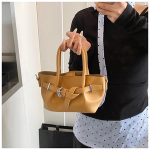 Détail du sac seau en cuir jaune avec sangles croisées et boucle en métal argenté