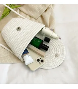 Detail showing spacious interior of white woven crossbody bag with phone and cosmetics