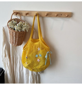 Detail of yellow woven mesh tote bag with starfish, shell charms and blue ribbon bow