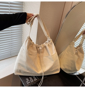 Detail view of large beige canvas tote bag showing waffle texture and drawstring closure