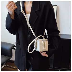 Detail of white mini box crossbody bag with crocodile embossed texture and dual zippers