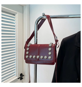 Detailed macro view of deep red oil wax leather and large silver rivets on the shoulder bag