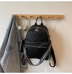 Close-up of black lychee leather backpack with geometric pattern woven strap and side pouch