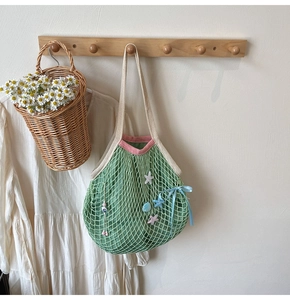Detail of green mesh tote with pink trim, starfish charm, and blue satin bow