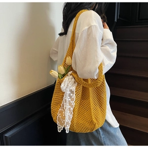 Détail du sac en tricot ajouré jaune avec nœud en dentelle et tulipes décoratives