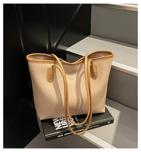 Close-up of beige tote bag with brown straps and Fashion Trend print on gray steps