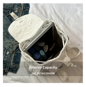 Vue détaillée de l'intérieur du sac à dos blanc à relief floral montrant le grand espace de rangement