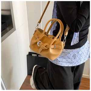 Détail du sac seau en cuir caramel avec boucle, poignée et bandoulière amovible
