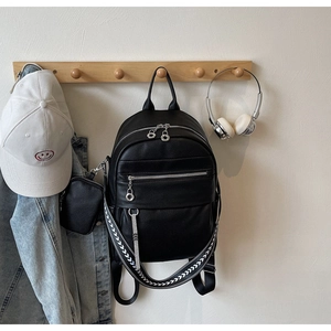 Detail of black lychee leather backpack with woven straps and silver metal zippers