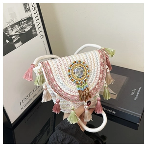 Dettaglio ravvicinato di una borsa a secchiello in paglia con nappe colorate e perline