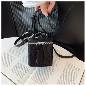 Detailed macro view of black crocodile texture mini box bag with silver zippers