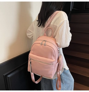 Detailed view of pink leather backpack with side pouch and patterned woven straps