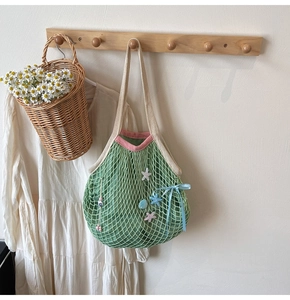 Detail of mint green mesh tote with starfish decor and floral charms on a wooden hanger