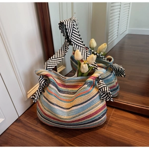 Dettaglio borsa tote in paglia colorata con motivo a righe e fiocco decorativo nero e bianco