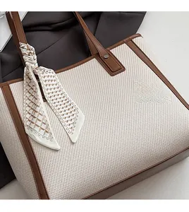 Detail of cream woven tote bag with brown leather handles and decorative silk scarf